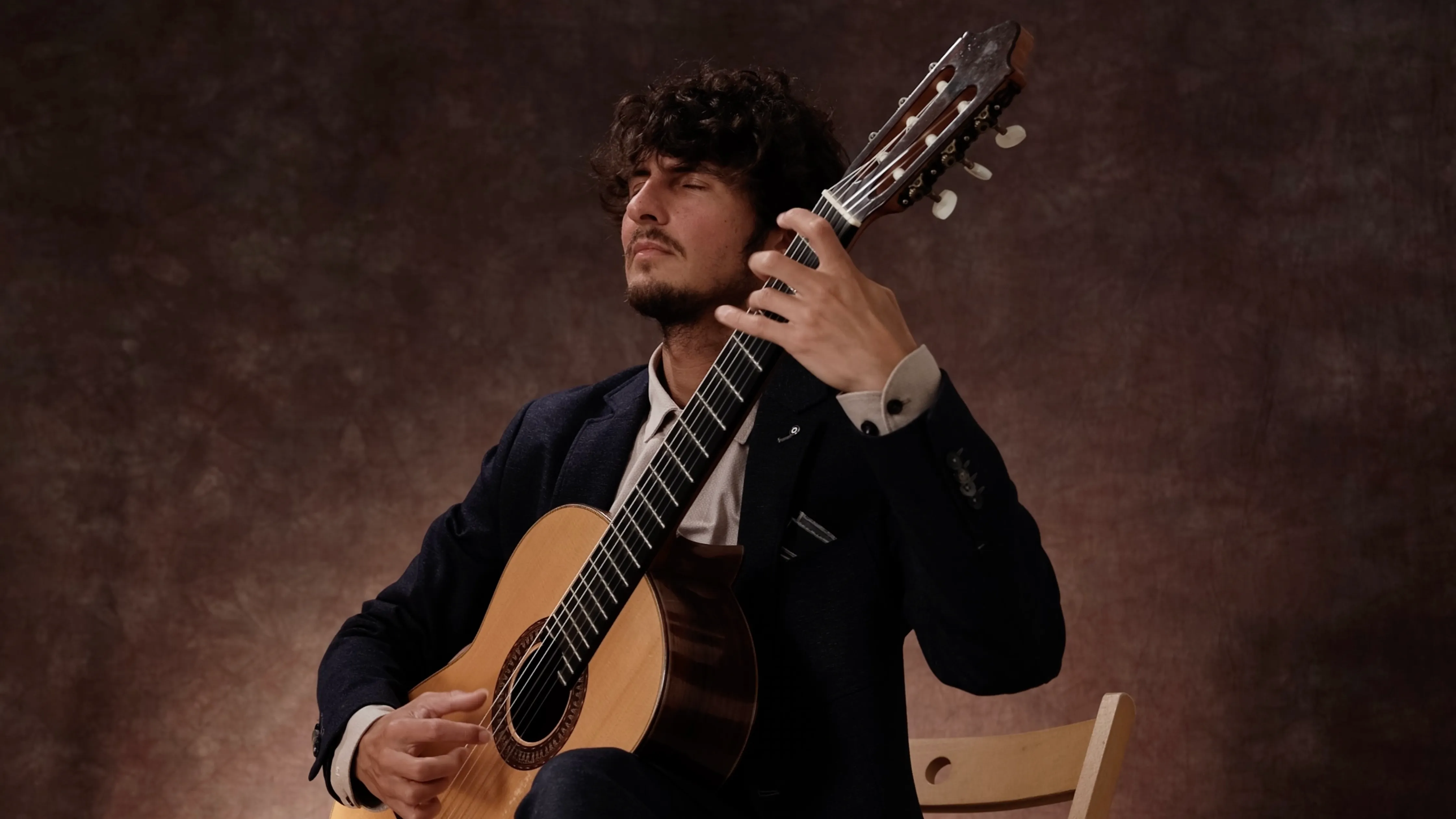 Silvan de Smit playing classical guitar in a studio portrait.